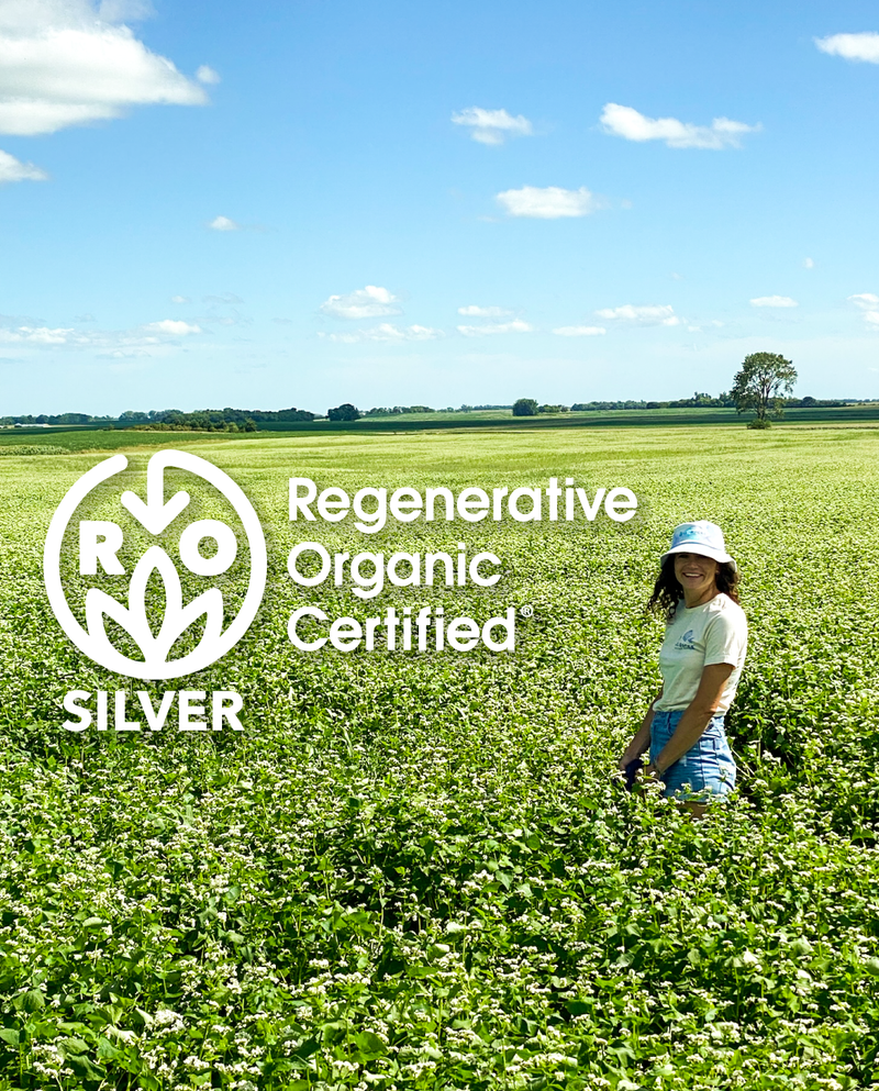 Emily in sprouted buckwheat field with regenerative organic certified logo